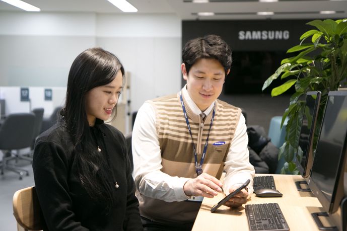 스마트폰을 점검받기 위해 서비스센터를 방문한 고객에게 제품 점검 후 친절하게 설명을 해주고 있는 모습